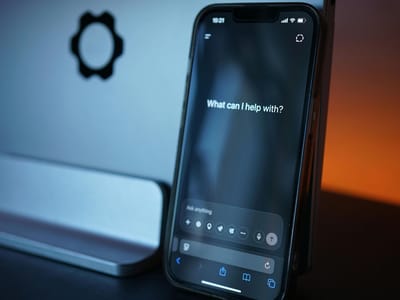A phone on a desk showing an AI assistant screen that asks What can I help with